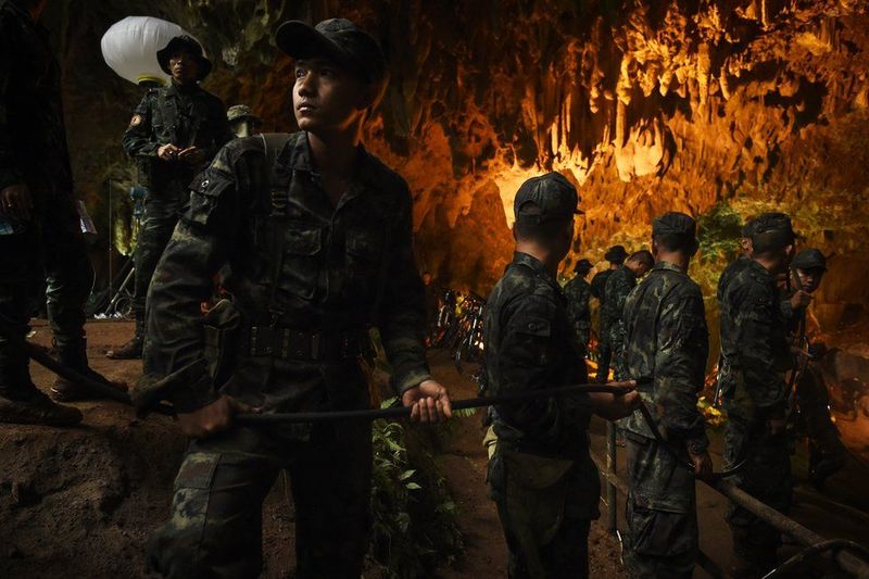 Солдаты опускают электрический кабель глубоко в затопленную пещеру на севере Таиланда в июне. Это проходит в рамках масштабной операции по спасению 12 мальчиков и их футбольного тренера, которые застряли в пещере. Спустя две недели их всех спасли. Фото: LILLIAN SUWANRUMPHA / AFP